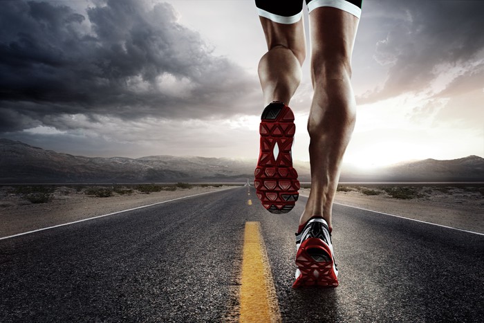 Sports background. Runner feet running on road closeup on shoe.